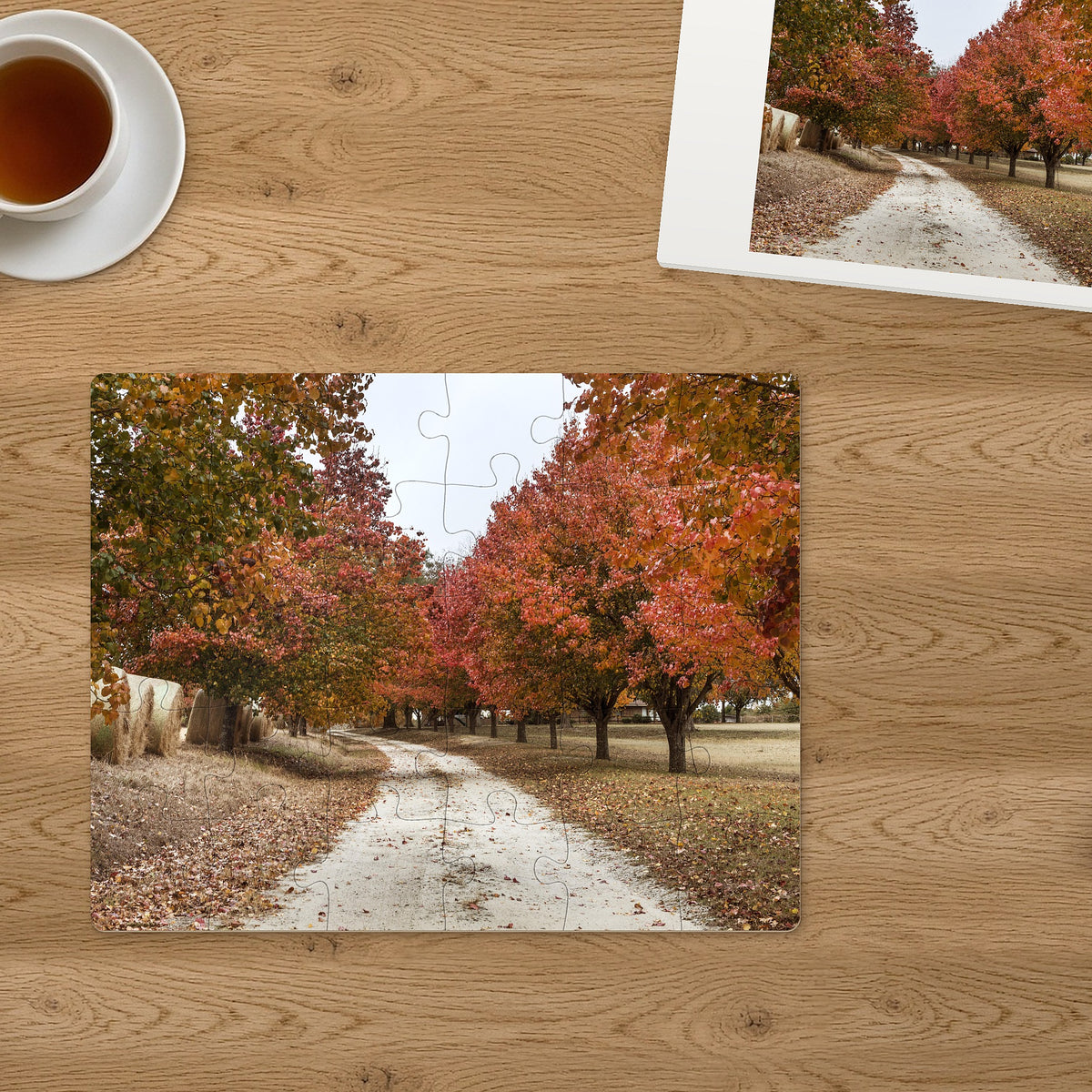 Memory Lane puzzle: Autumn Country Lane. The finished 30-piece 14″ × 11″ puzzle on a table beside its white gift box (product illustration)