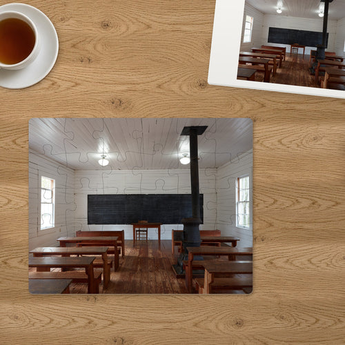 Memory Lane puzzle: One-Room Schoolhouse. The finished 30-piece 14″ × 11″ puzzle on a table beside its white gift box (product illustration)