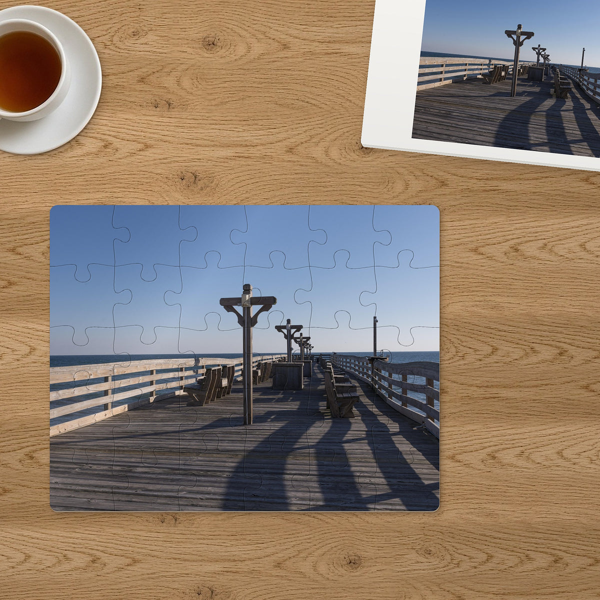 Memory Lane puzzle: Seaside Pier. The finished 30-piece 14″ × 11″ puzzle on a table beside its white gift box (product illustration)